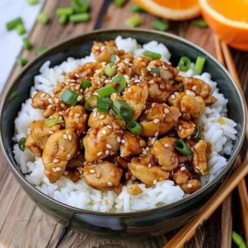 Plate of ground orange chicken served with rice and vegetables
