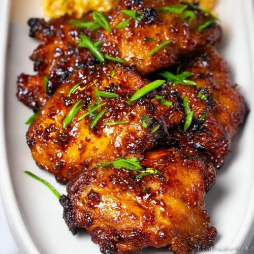Plate of honey garlic chicken thighs glazed with sweet and savory sauce.
