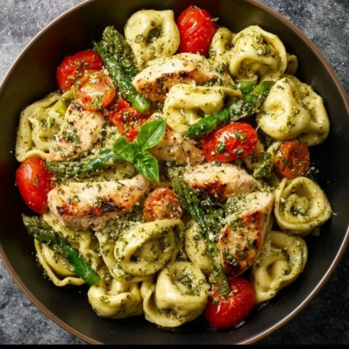 A delicious one-pan pesto chicken tortellini meal garnished with fresh basil.